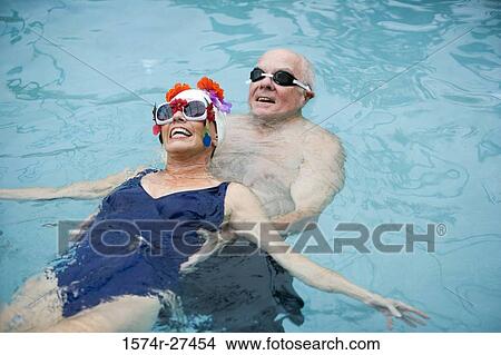 Cheerful senior couple swimming in a swimming pool View Large Photo Image Picture - Cheerful senior couple swimming in a swimming pool. Fotosearch