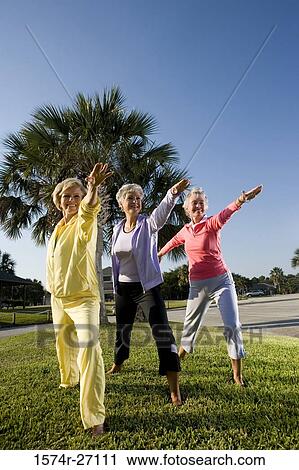 Cheerful senior woman exercising on grass with arms outstretched View Large Photo Image Stock Image - Cheerful senior woman exercising on grass with arms outstretched. Fotosearch
