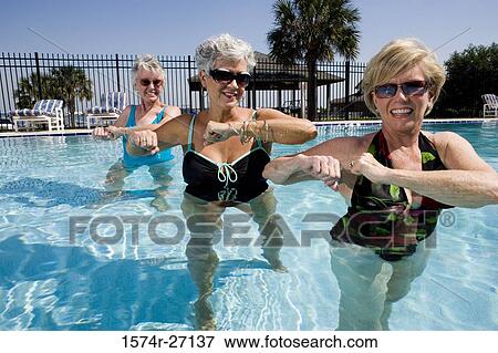 Cheerful senior women exercising in swimming pool View Large Photo Image Stock Photo - Cheerful senior women exercising in swimming pool. Fotosearch