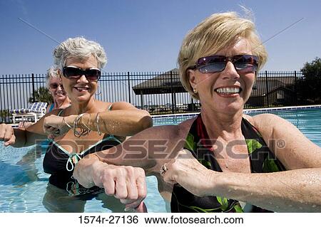 Cheerful senior women exercising in swimming pool View Large Photo Image Stock Photograph - Cheerful senior women exercising in swimming pool. Fotosearch