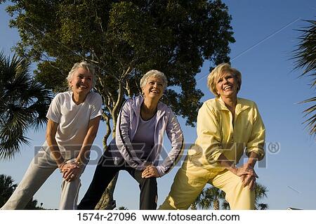 Cheerful senior women exercising with hand on knee View Large Photo Image Stock Photograph - Cheerful senior women exercising with hand on knee. Fotosearch