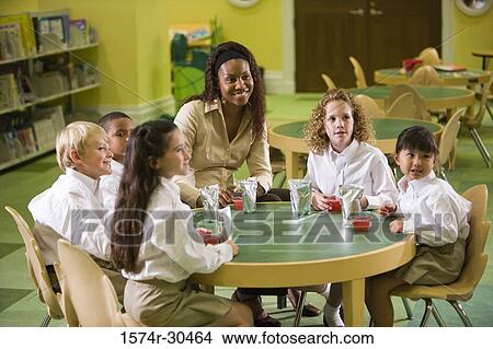 Picture - Cheerful teacher having refreshment with students. Fotosearch