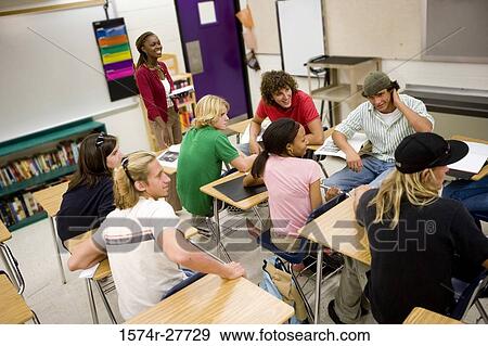 Cheerful teacher holding book and teaching in the classroom View Large Photo Image Stock Photo - Cheerful teacher holding book and teaching in the classroom. Fotosearch