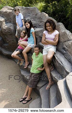 Cheerful teenage boys and girls sitting on rocks View Large Photo Image Stock Photo - Cheerful teenage boys and girls sitting on rocks. Fotosearch