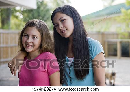 Cheerful teenage girls standing in the petting zoo with arm around View Large Photo Image Picture - Cheerful teenage girls standing in the petting zoo with arm around. Fotosearch