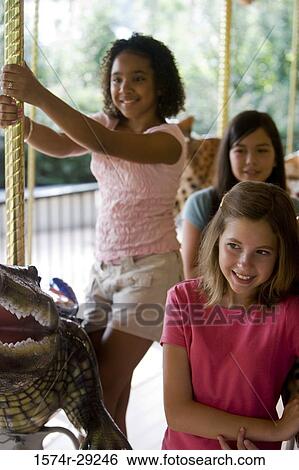 Cheerful teenage girls standing on a carousel View Large Photo Image Stock Photograph - Cheerful teenage girls standing on a carousel. Fotosearch