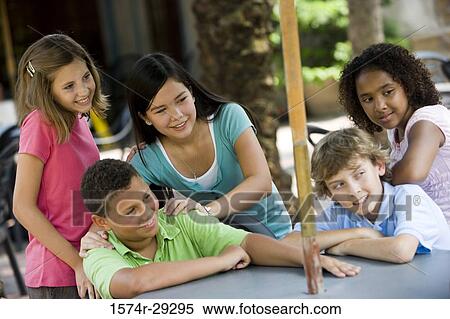 Stock Photography - Cheerful teenagers sitting by a table. Fotosearch