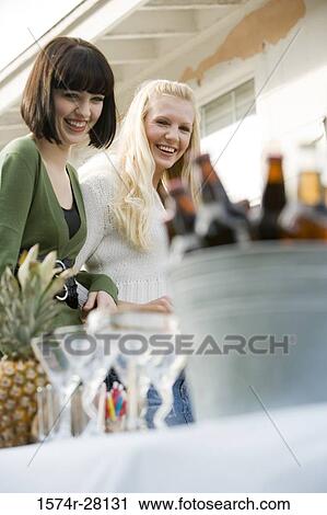 Cheerful women looking wineglasses by table View Large Photo Image Stock Image - Cheerful women looking wineglasses by table. Fotosearch