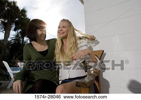 Cheerful women sitting on armchair View Large Photo Image Stock Photograph - Cheerful women sitting on armchair. Fotosearch