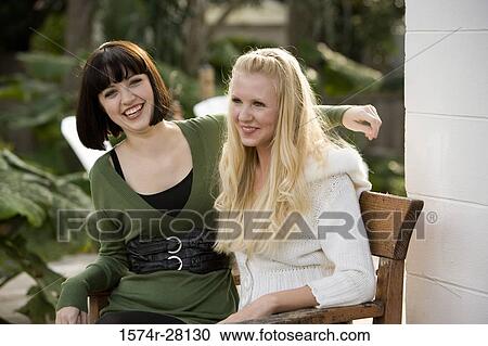Cheerful women sitting on armchairs by wall View Large Photo Image Stock Image - Cheerful women sitting on armchairs by wall. Fotosearch