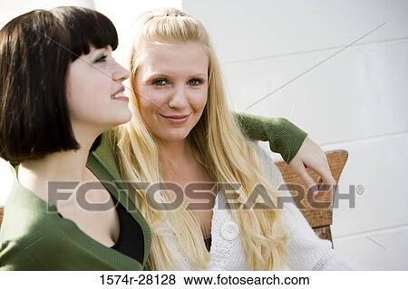 Cheerful women with arm around by wall View Large Photo Image Stock Photo - Cheerful women with arm around by wall. Fotosearch