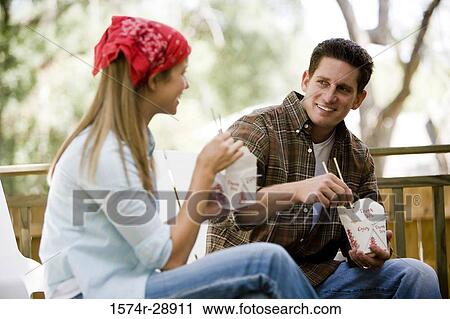 Cheerful young couple eating noodles on armchairs View Large Photo Image Stock Image - Cheerful young couple eating noodles on armchairs. Fotosearch