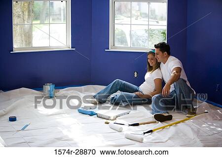 Cheerful young couple sitting by paint tray and paint roller in house View Large Photo Image Stock Image - Cheerful young couple sitting by paint tray and paint roller in house. Fotosearch