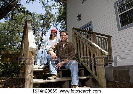 Stock Photo - Cheerful young couple sitting together on staircase. Fotosearch