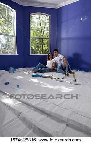 Cheerful young couple sitting with paint tray and paint roller on drop cloth in house View Large Photo Image Stock Photograph - Cheerful young couple sitting with paint tray and paint roller on drop cloth in house. Fotosearch