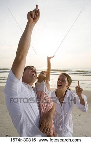 Cheerful young couple with daughter on the beach View Large Photo Image Stock Photograph - Cheerful young couple with daughter on the beach. Fotosearch