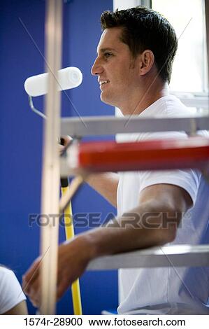 Cheerful young man holding a paint roller by step ladder View Large Photo Image Stock Image - Cheerful young man holding a paint roller by step ladder. Fotosearch