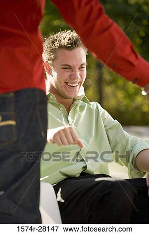 Cheerful young man sitting on armchair View Large Photo Image Stock Photo - Cheerful young man sitting on armchair. Fotosearch