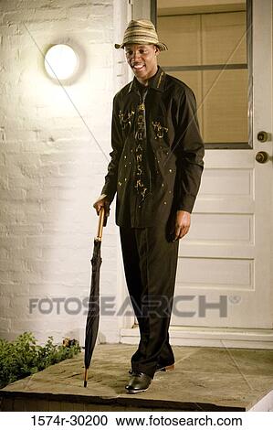 Cheerful young man standing in front of the door and holding an umbrella View Large Photo Image Stock Image - Cheerful young man standing in front of the door and holding an umbrella. Fotosearch