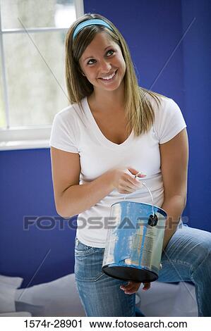 Cheerful young woman holding paint can and looking up View Large Photo Image Stock Image - Cheerful young woman holding paint can and looking up. Fotosearch