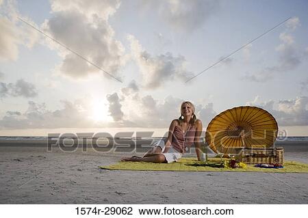 Cheerful young woman sitting at the beach View Large Photo Image Stock Image - Cheerful young woman sitting at the beach. Fotosearch