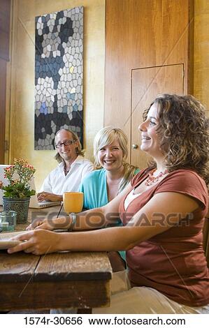 Cheerful young woman sitting with parents by table View Large Photo Image Stock Photograph - Cheerful young woman sitting with parents by table. Fotosearch