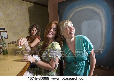 Cheerful young woman with mother by bar counter with sister behind View Large Photo Image Stock Photo - Cheerful young woman with mother by bar counter with sister behind. Fotosearch