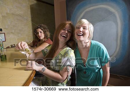 Cheerful young woman with mother by bar counter with sister behind View Large Photo Image Stock Photo - Cheerful young woman with mother by bar counter with sister behind. Fotosearch