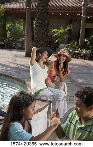 Cheerful young women sitting by water while children in foreground View Large Photo Image Stock Photography - Cheerful young women sitting by water while children in foreground. Fotosearch