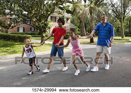 Children holding hands of their parents while walking on the road View Large Photo Image Picture - Children holding hands of their parents while walking on the road. Fotosearch