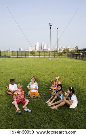 Children sitting on grass and eating lollipops View Large Photo Image Stock Image - Children sitting on grass and eating lollipops. Fotosearch
