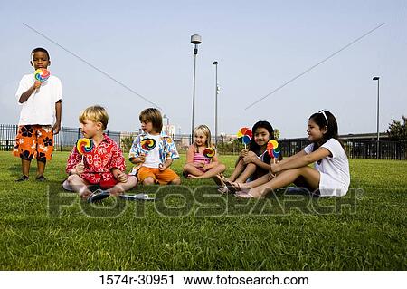 Children sitting on grass and eating lollipops View Large Photo Image Stock Image - Children sitting on grass and eating lollipops. Fotosearch