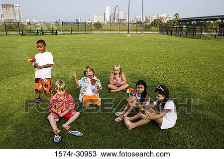 Children sitting on grass and eating lollipops View Large Photo Image Stock Image - Children sitting on grass and eating lollipops. Fotosearch