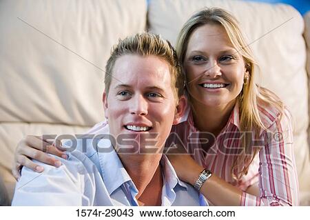 Stock Image - Close-up of a cheerful mid adult couple looking away in a house. Fotosearch