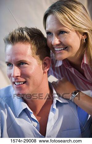 Close-up of a cheerful mid adult couple looking away in a house View Large Photo Image Stock Photo - Close-up of a cheerful mid adult couple looking away in a house. Fotosearch