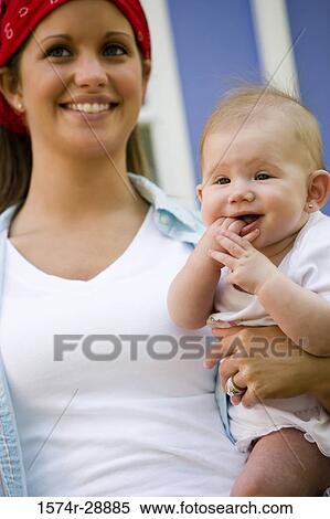 Close-up of a cheerful young woman holding her baby View Large Photo Image Stock Photography - Close-up of a cheerful young woman holding her baby. Fotosearch