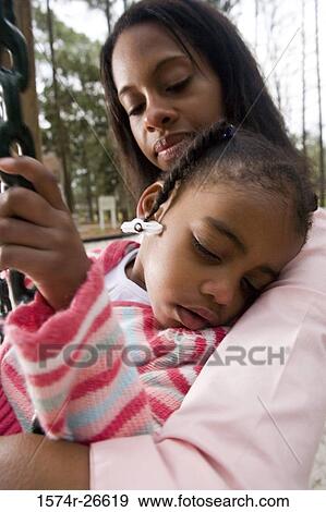Close-up of a daughter sleeping in her mother's arms at park View Large Photo Image Stock Photo - Close-up of a daughter sleeping in her mother's arms at park. Fotosearch