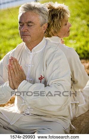 Stock Image - Close-up of a mature couple meditating in praying position. Fotosearch