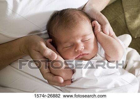 Stock Image - Close-up of a newborn baby in human hand. Fotosearch