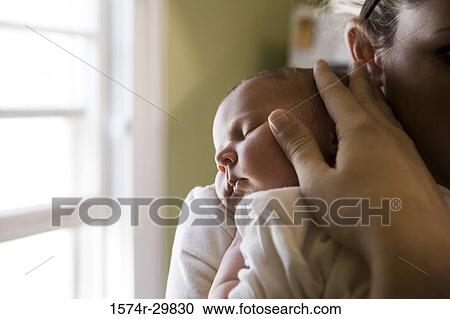 Stock Image - Close-up of a young woman holding her baby. Fotosearch