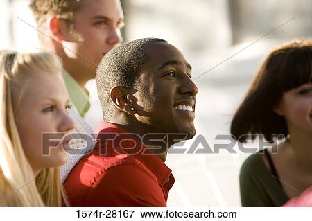 Stock Photo - Close-up of cheerful friends looking away. Fotosearch