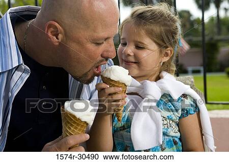 Close-up of daughter offering her father an ice cream cone View Large Photo Image Stock Image - Close-up of daughter offering her father an ice cream cone. Fotosearch