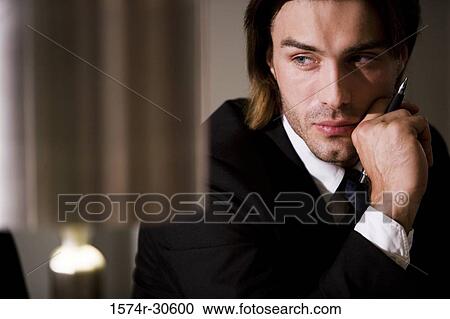 Contemplative businessman holding pen and looking away in an office View Large Photo Image Stock Image - Contemplative businessman holding pen and looking away in an office. Fotosearch