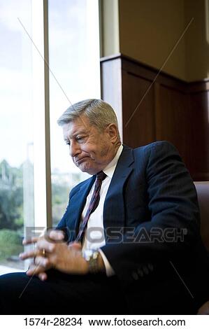 Contemplative businessman sitting on armchair in an office View Large Photo Image Picture - Contemplative businessman sitting on armchair in an office. Fotosearch