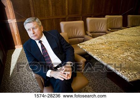 Contemplative businessman sitting on armchair in an office View Large Photo Image Stock Photograph - Contemplative businessman sitting on armchair in an office. Fotosearch