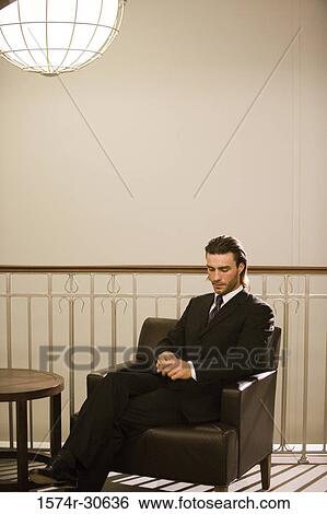 Stock Photograph - Contemplative businessman sitting on armchair in an office. Fotosearch