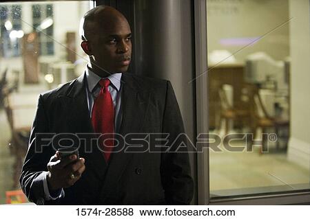 Contemplative businessman using a mobile phone out of a office View Large Photo Image Stock Photo - Contemplative businessman using a mobile phone out of a office. Fotosearch