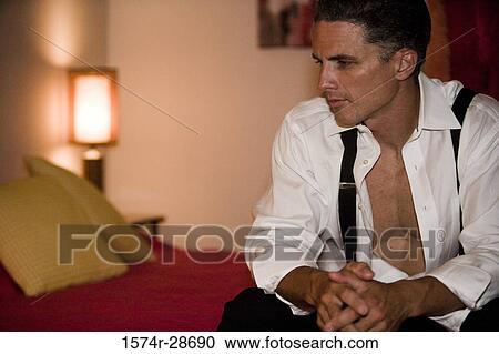 Contemplative mid adult man sitting on bed in the bedroom View Large Photo Image Stock Image - Contemplative mid adult man sitting on bed in the bedroom. Fotosearch