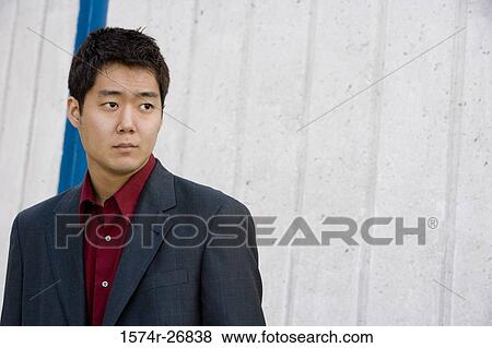Contemplative young businessman in front of wall View Large Photo Image Stock Photo - Contemplative young businessman in front of wall. Fotosearch