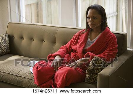 Contemplative young woman in gown sitting on a sofa View Large Photo Image Stock Image - Contemplative young woman in gown sitting on a sofa. Fotosearch